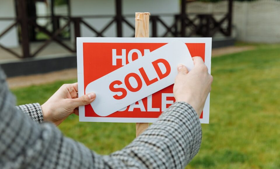 Shallow Focus Photo of a Realtor Posting a Sold Sticker
